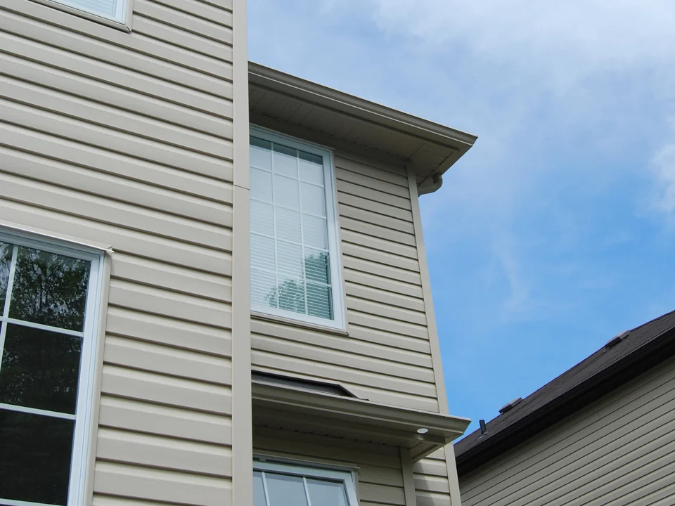 Horizontal vinyl siding courses, window trim, and soffit on a house