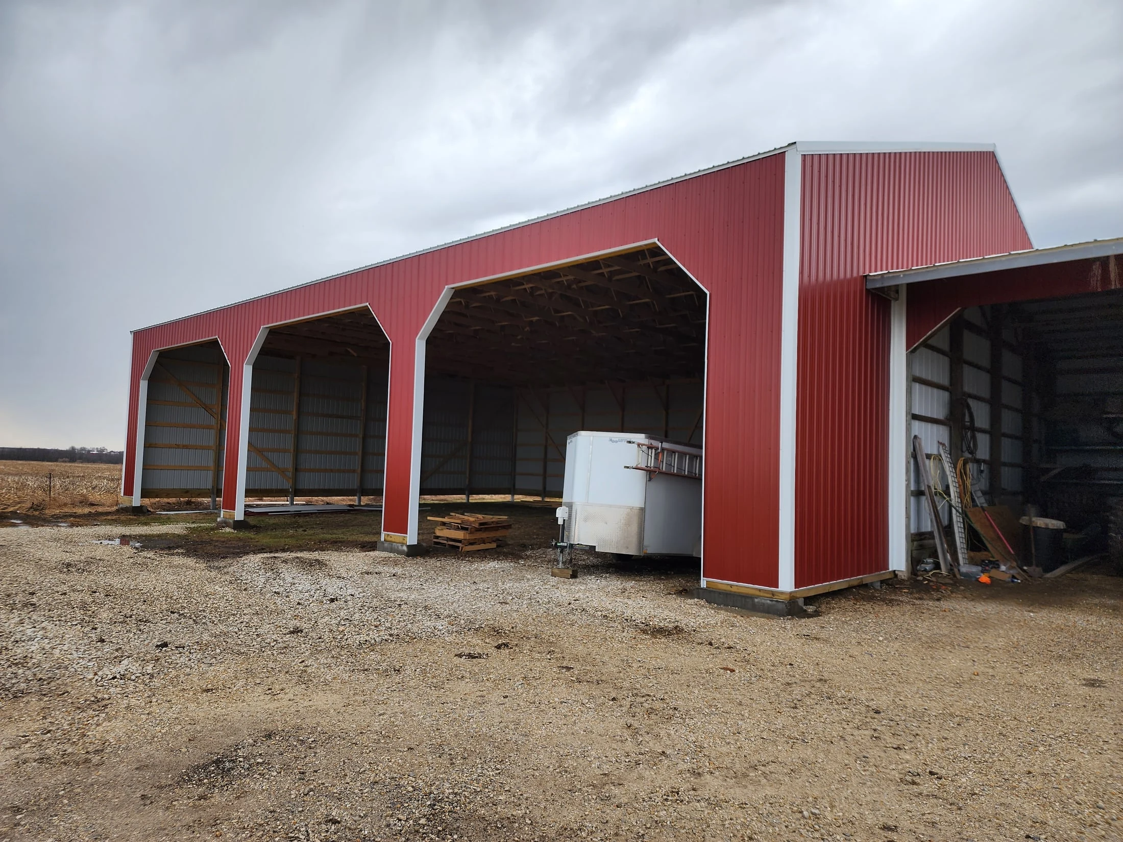 Bontrager agricultural building with red metal siding and open covered equipment bays